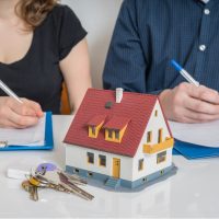 Couple discussing property division in divorce with model house and keys, symbolizing family law issues related to spousal support and custody in Illinois.