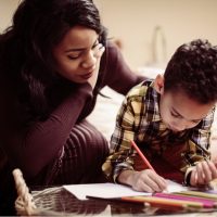 Mother assisting child with homework, emphasizing parental involvement in child development and custody considerations in family law.