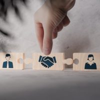 divorce Hand placing puzzle piece with handshake symbol between two figures, representing cooperation and resolution in divorce proceedings, relevant to family law and divorce guidance.