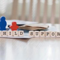 child support Child support concept with letter blocks spelling "CHILD SUPPORT" and figurines representing parents and children, highlighting family law issues in Illinois.