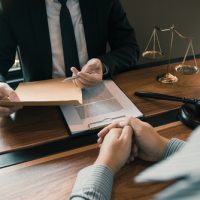 divorce Attorney consulting with client about divorce proceedings, legal documents on table, scales of justice in background, emphasizing family law guidance.