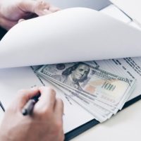 asset division Hands holding documents with cash underneath, symbolizing hidden assets in divorce proceedings in Illinois.