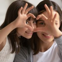 Mother and daughter making heart shape with hands, symbolizing love and family connection, relevant to family law discussions.