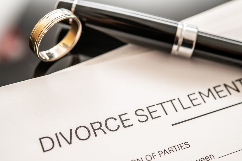 DivorceSettlementAgreementPaperworkDisplayedAlongsideAWeddingRingAnd DivorceSettlementAgreementPaperworkDisplayedAlongsideAWeddingRingAnd