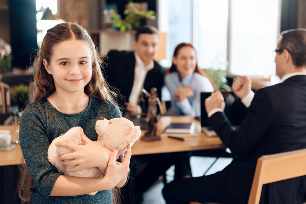 HappyLittleGirlIsHuggingTeddyBearAtOfficeOf