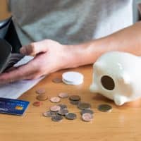 Person counting coins next to a piggy bank and a credit card, symbolizing financial considerations during divorce proceedings in Illinois.