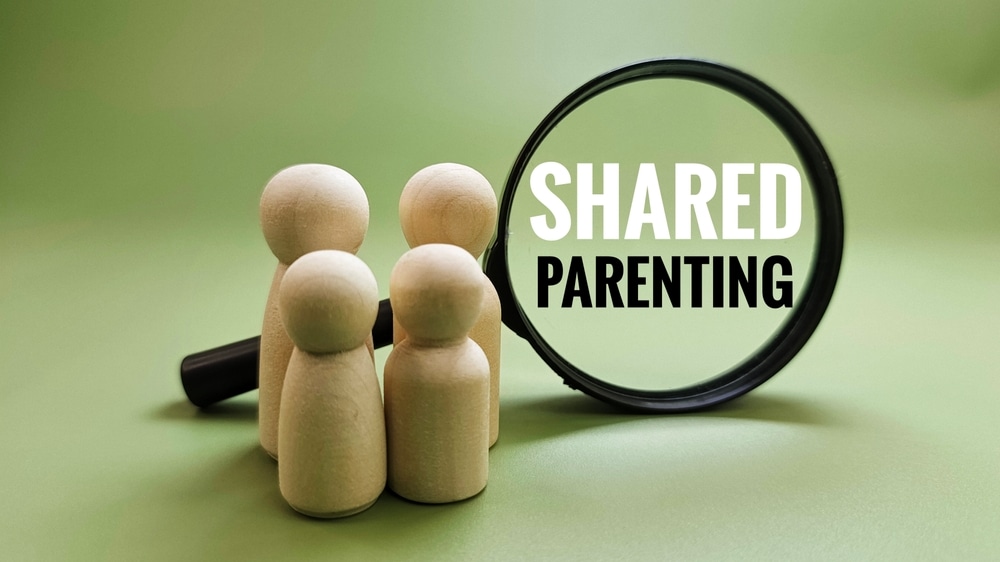 SharedParentingConceptWithWoodenDollsFamilyAndMagnifyingGlass SharedParentingConceptWithWoodenDollsFamilyAndMagnifyingGlass