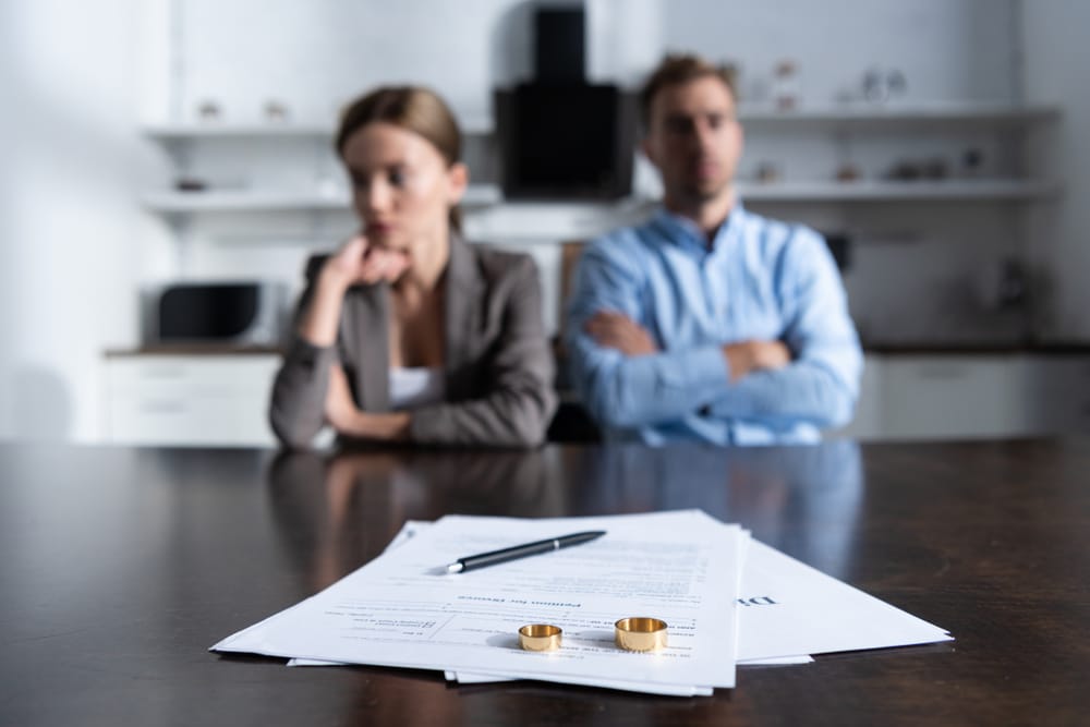 SelectiveFocusOfCoupleSittingAtTableWithDivorceDocuments