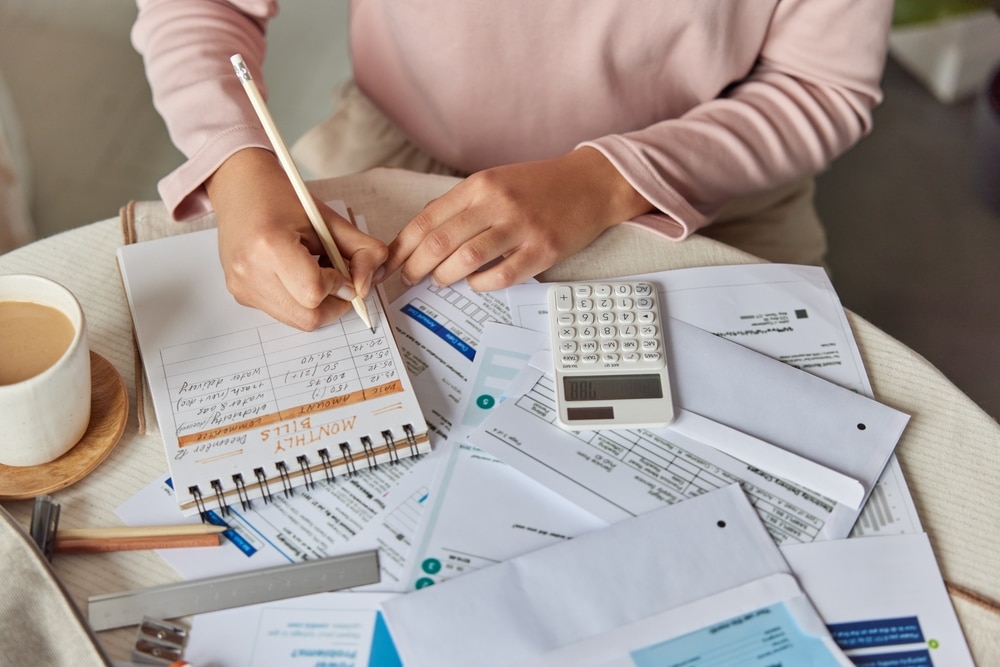 UnrecognizableWomanManagesHouseholdBudgetOrExpendituesStudiesMonthlyBills UnrecognizableWomanManagesHouseholdBudgetOrExpendituesStudiesMonthlyBills