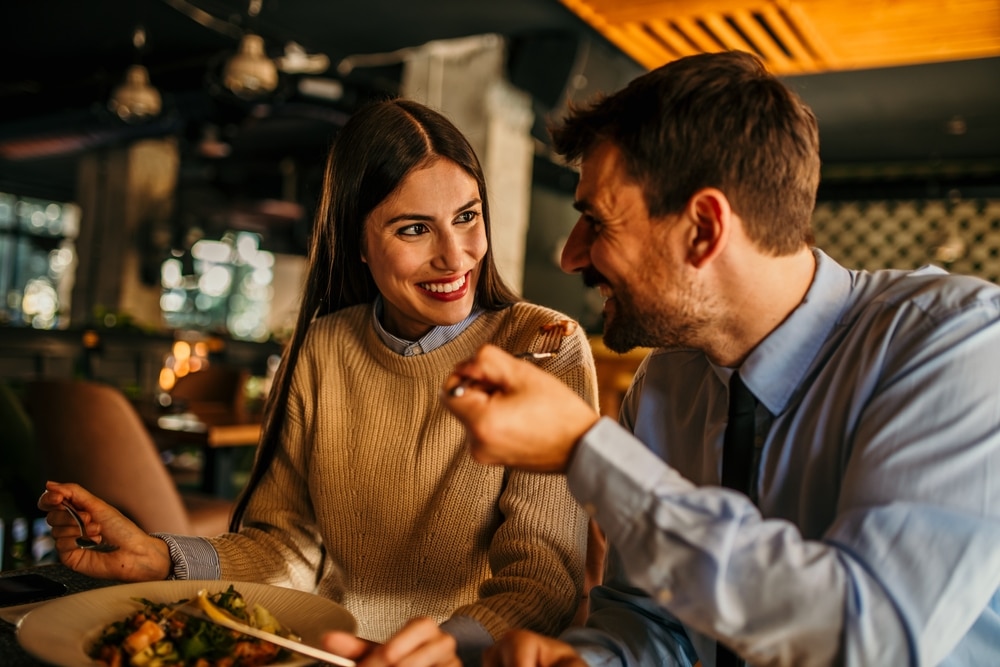 ALovingCoupleLaughingWhileEatingInTheRestaurantAfterwork ALovingCoupleLaughingWhileEatingInTheRestaurantAfterwork